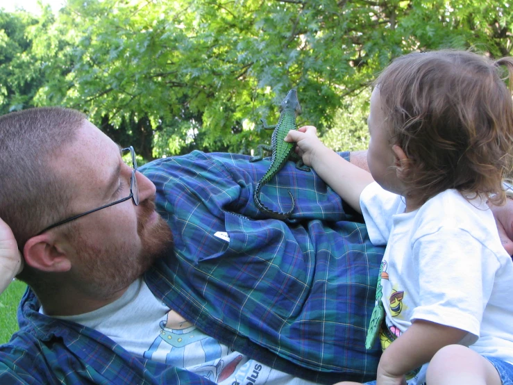 a man wearing glasses and holding a child up to the ground