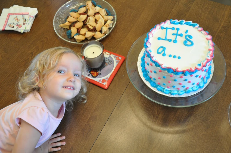 little girl smiling beside a homemade birthday cake