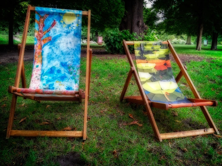 two wooden lawn chairs in a green grass park