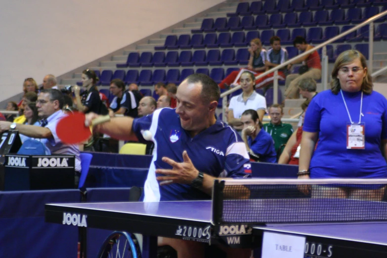 a man standing next to a ping pong table