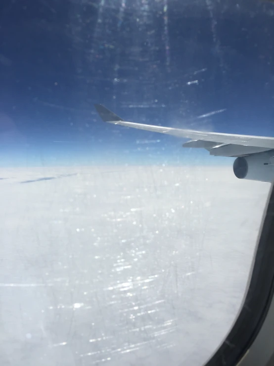 an airplane window showing the wing of a plane