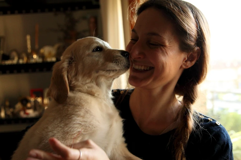 a woman is holding a puppy smiling