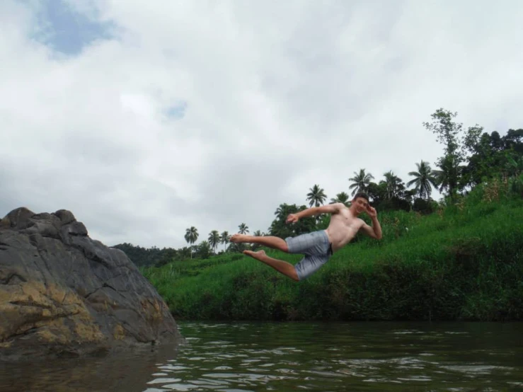 a man jumps off rocks into a river