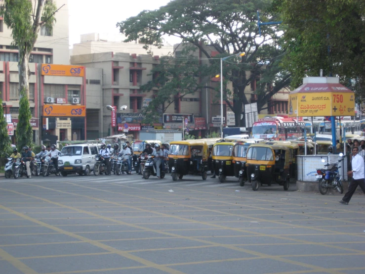 several buses and people waiting for the traffic to change