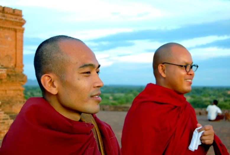 two men who are wearing red robes and staring ahead