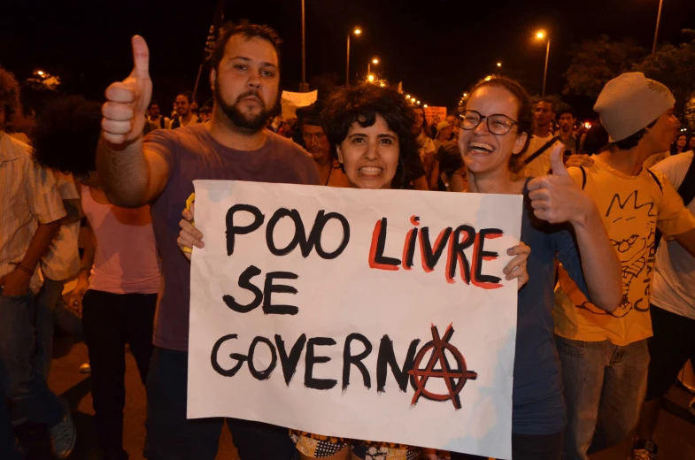 two people hold signs while standing in the crowd at a public event