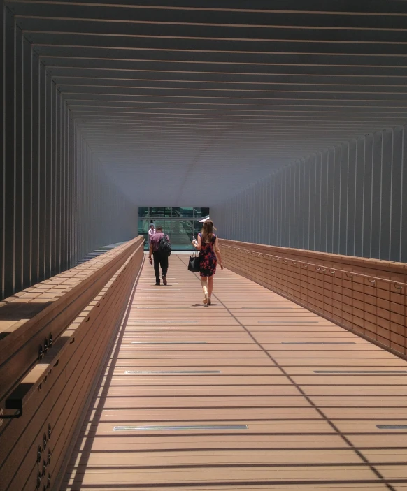 people walking across the bridge near a building