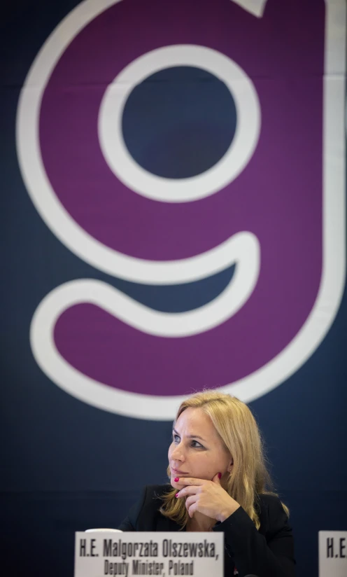 a person sitting at a table in front of a sign