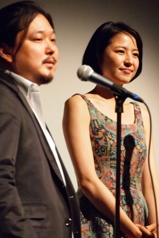 a man standing next to a woman at a microphone