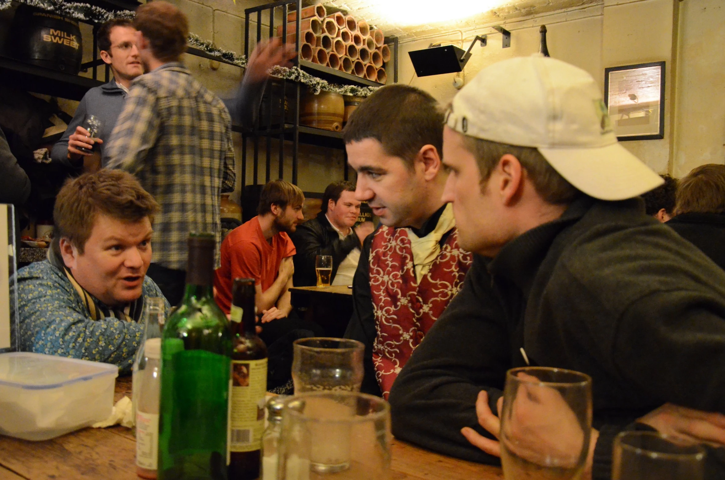 a group of men sitting at a table with bottles and wine glasses