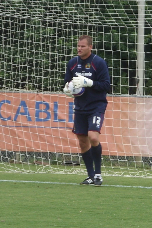 the player in the blue uniform is warming up by the goal