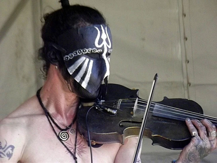 man wearing skull mask holding a violin in his hand
