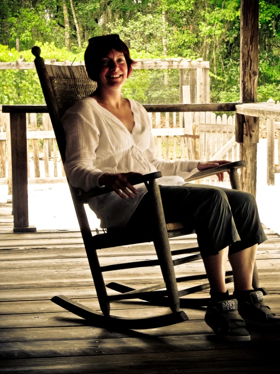 an older woman smiles sitting on a rocking chair