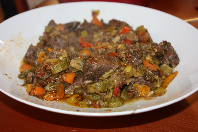 a white bowl with cooked meat and vegetables