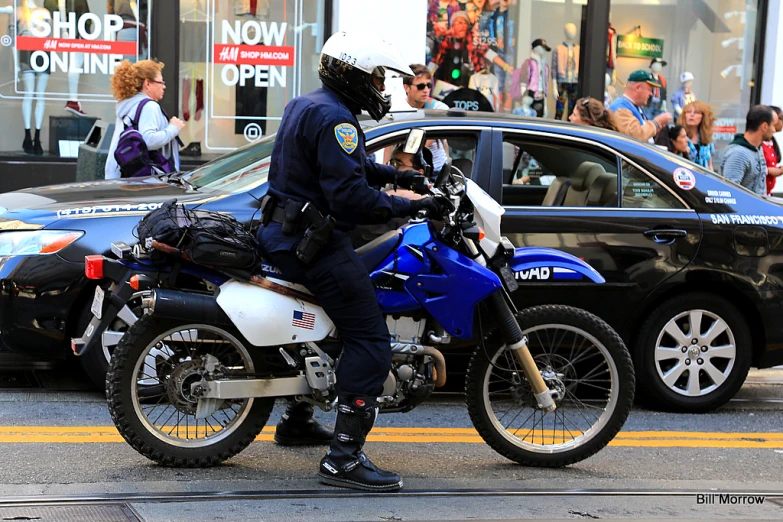 a cop standing on top of his motorcycle next to a police car