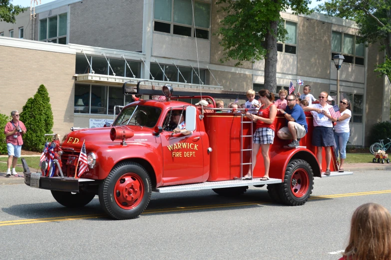 a very big pretty fire truck with a bunch of people on top of it