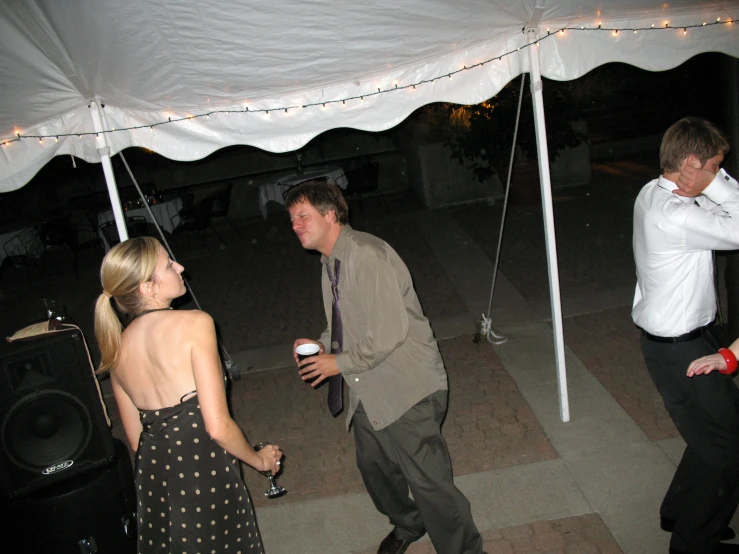 three young men and a woman having a party under a white tent