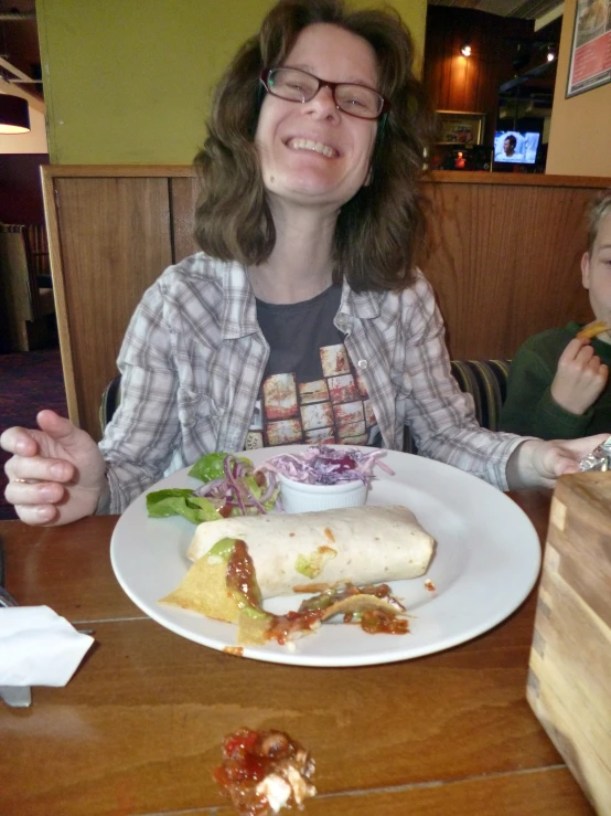 a girl with glasses sitting in front of a plate with food