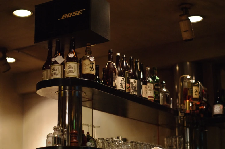 bottles on a shelf and empty glasses next to the wall