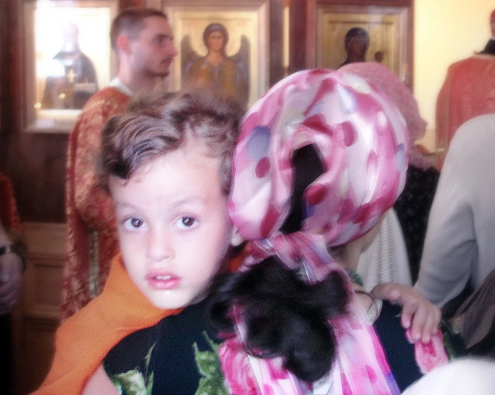 little boy with scarf holding up a black cat