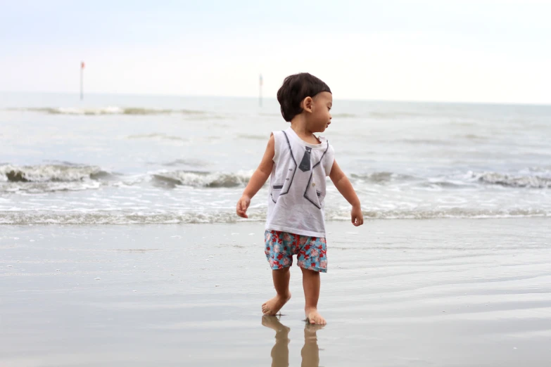 a boy is walking on the beach while holding an item in his hand