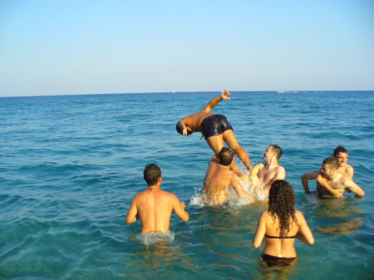 a man in black swimming trunks jumps into the ocean