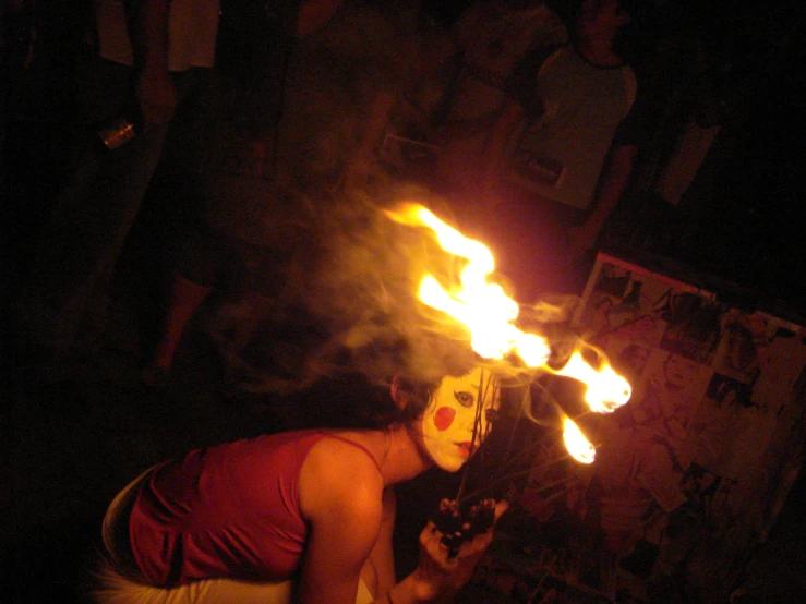 a woman wearing red shirt blowing flames in her hair
