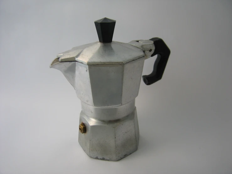 a silver colored stovetop coffee pot sitting on top of a white table