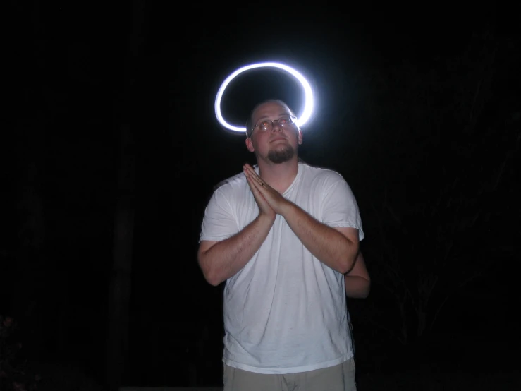 man with hands up in the air near a small ring of light