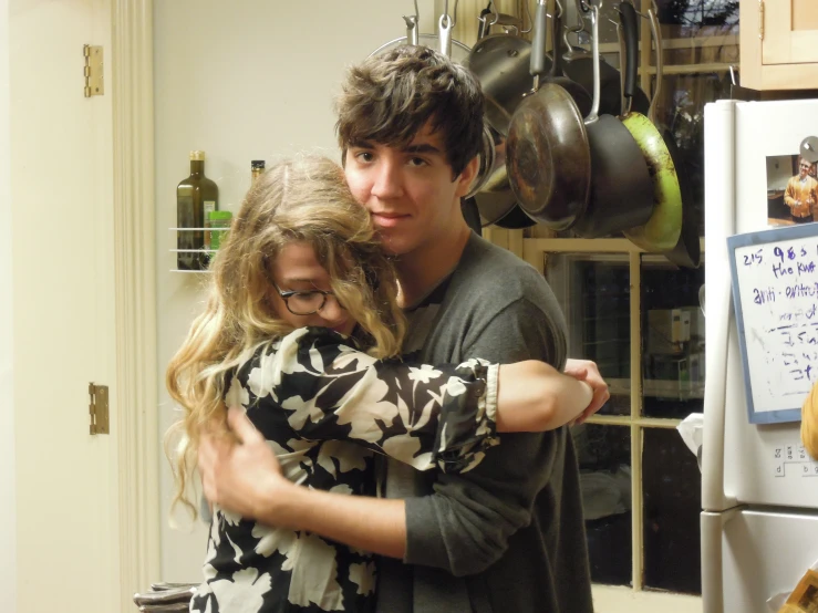 a man and woman hugging in the kitchen