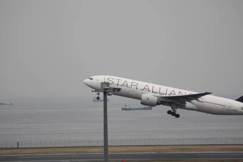 an airplane landing near the ocean on a cloudy day