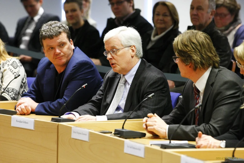 people sitting at table in front of the microphones