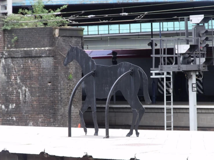 a horse statue near a building near an elevated walkway