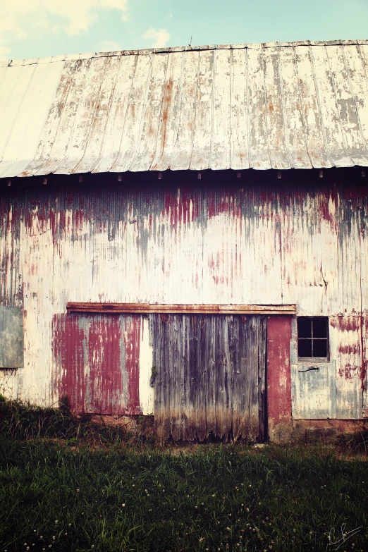 the side of an old red and white barn with open windows