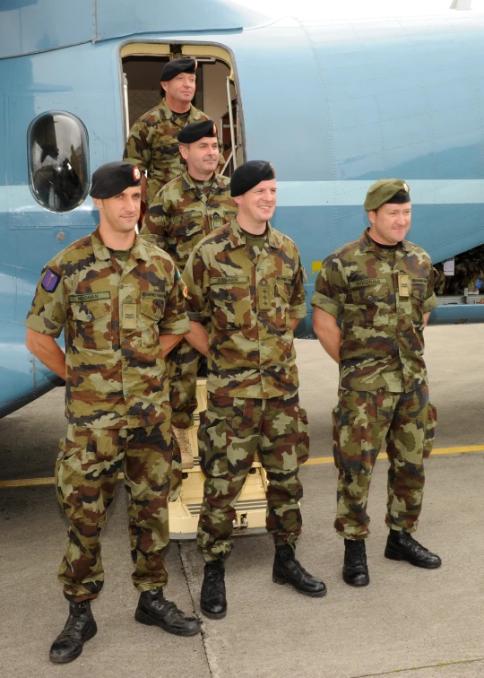 a group of people in uniform standing next to an airplane