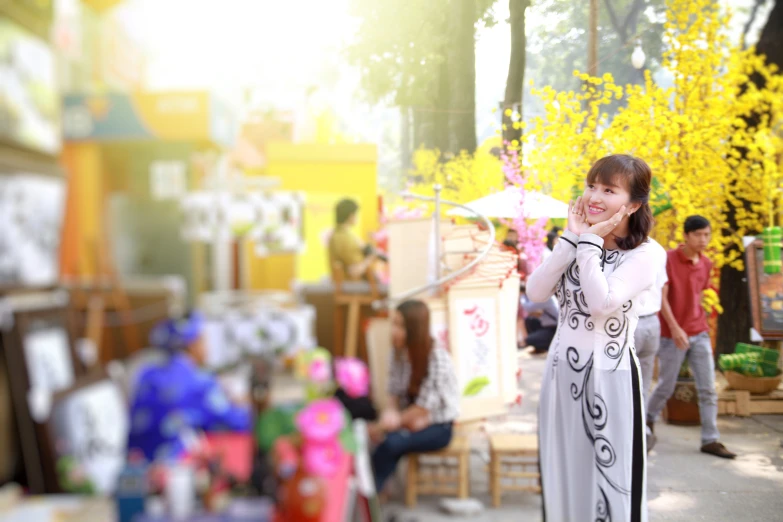 a woman talking on a phone in front of a store with lots of fake trees