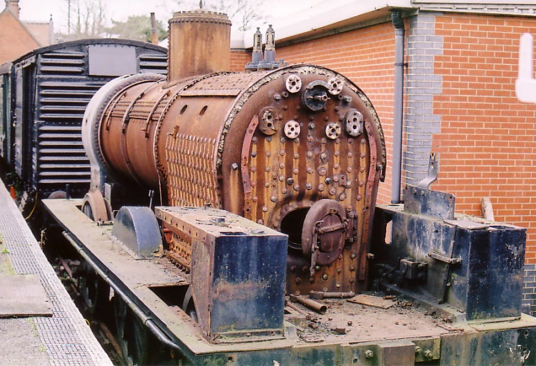 a rusted steam locomotive is parked near a building