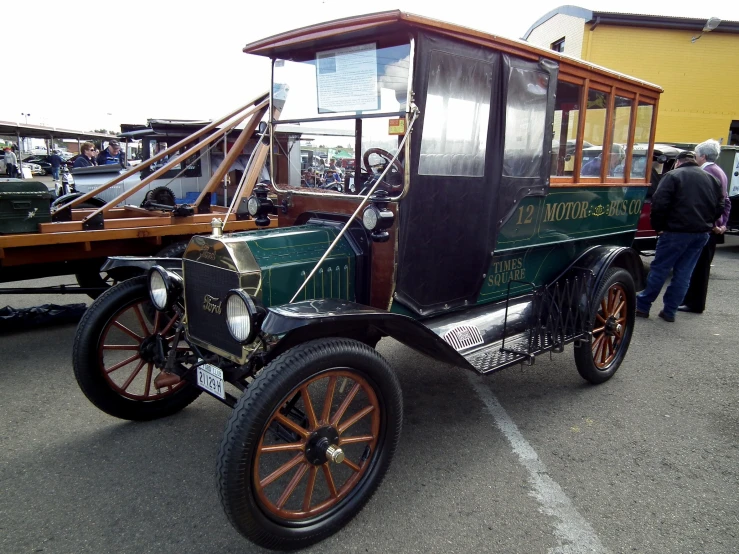 an old fashioned, green and gold car is parked in a lot