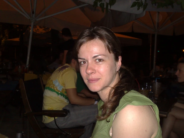 a girl sitting under an umbrella outside smiling