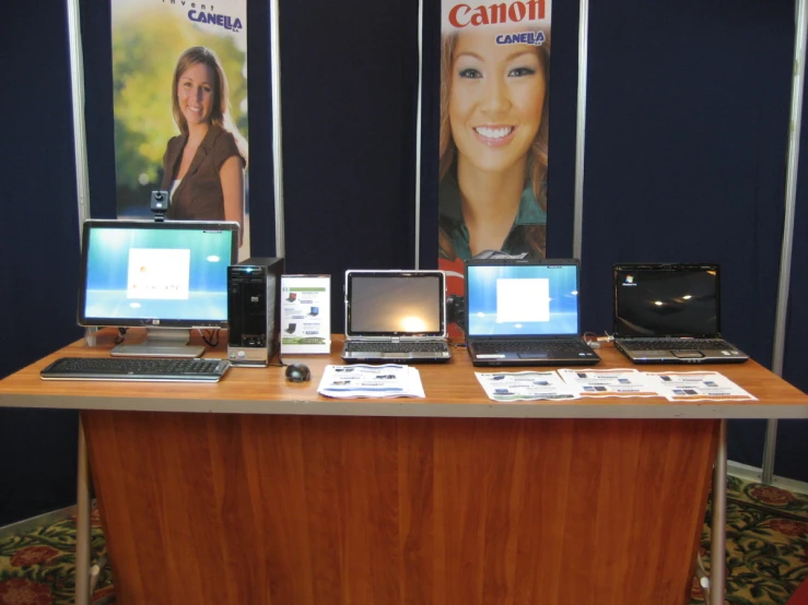 there are many computers on the table with posters above