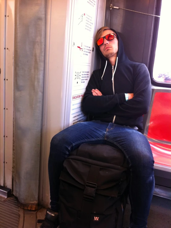 there is a man wearing a hoodie sitting on the subway