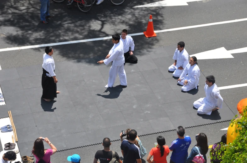 people dressed in white sitting and standing on the street with their backs to each other