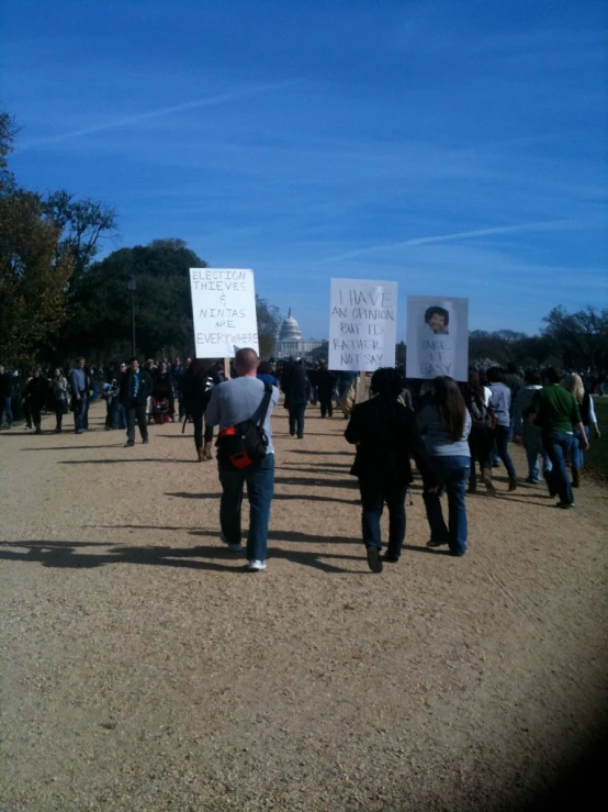 protestors holding up posters with images of obama and nixon
