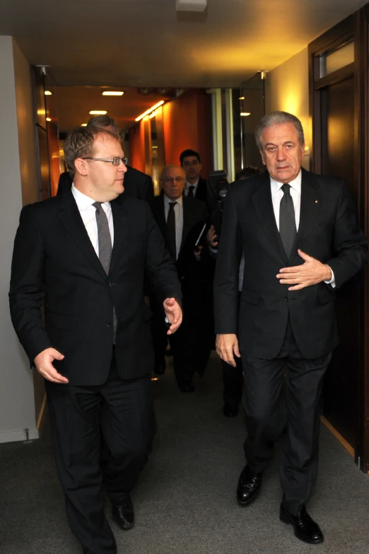 two men in suits and ties standing by the door