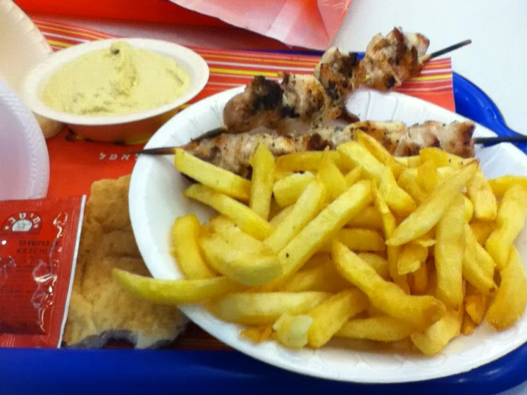 a plate filled with fries and chicken next to dipping sauce