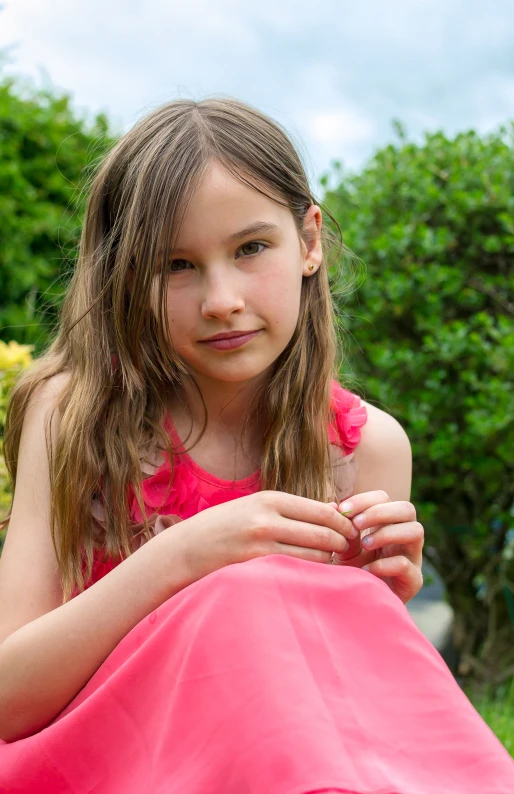 little girl sitting outside in the sun holding her hands together