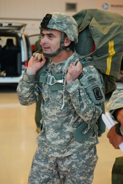 a military man is carrying soing in his backpack