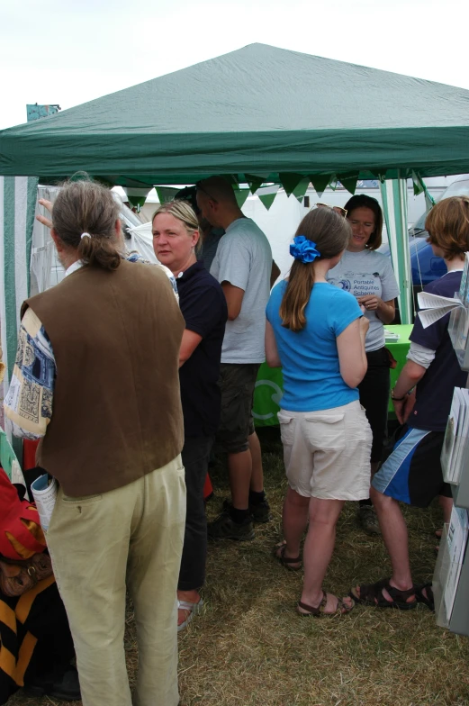 group of people standing under tent in a grassy area