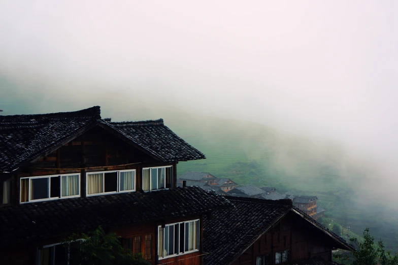 a view of a town through some mist covered mountains