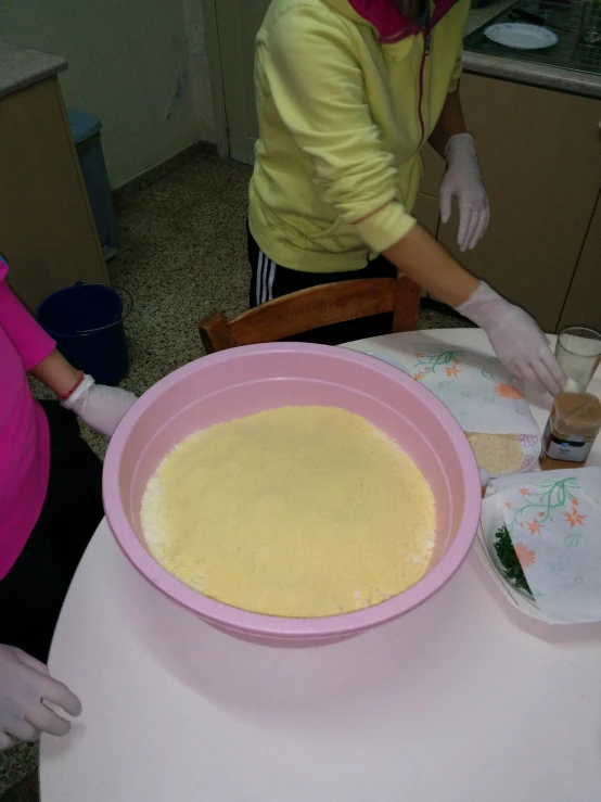 a woman pouring batter on top of a pink cake plate